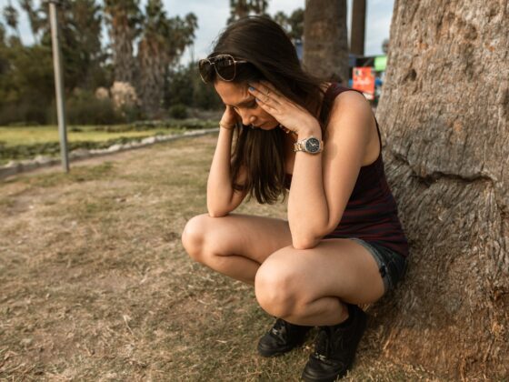 photo of a woman crouching while her hands are on her head
