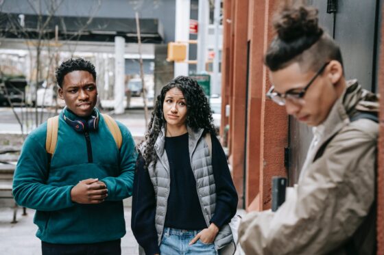 multiethnic friends bullying male classmate on street