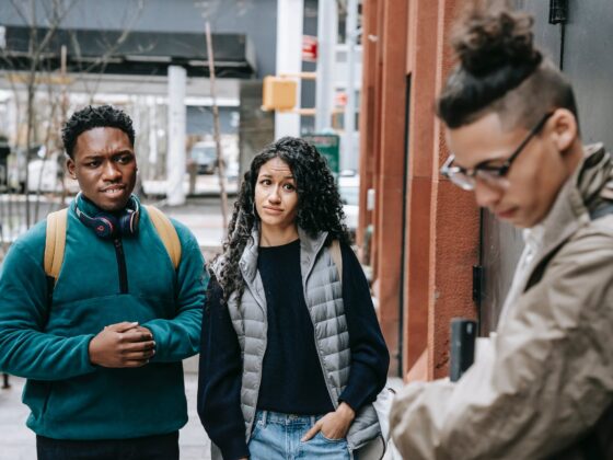 multiethnic friends bullying male classmate on street