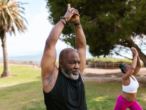 an elderly man in black tank top raising his hands together