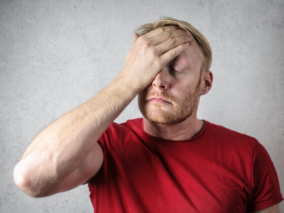 a man in red shirt covering his face