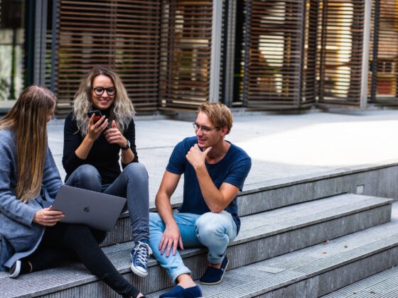 three persons sitting on the stairs talking with each other