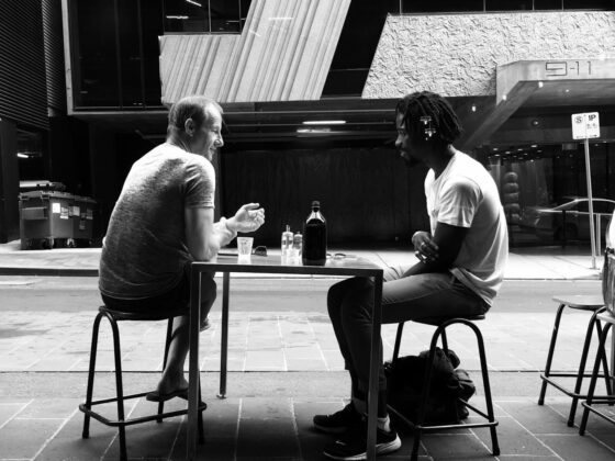 photo of two men talking while sitting on chair