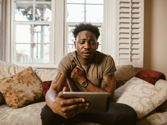 emotional man sitting on couch watching a video on tablet
