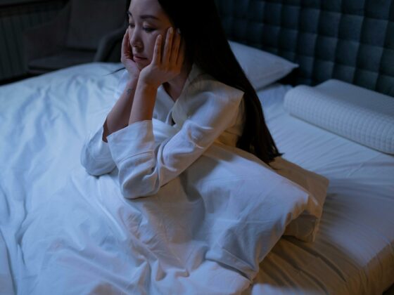 woman in white long sleeve shirt sitting on a bed