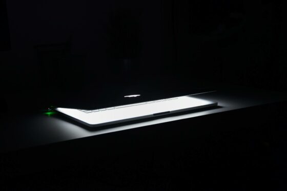 photography of macbook half opened on white wooden surface